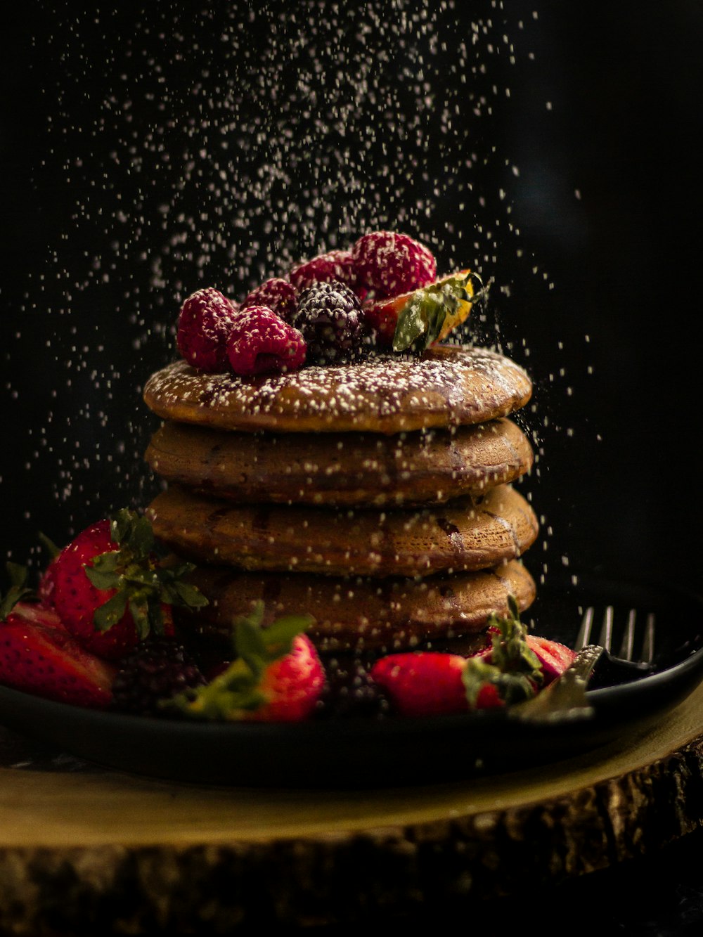 pancakes with strawberries and blueberries on black ceramic plate