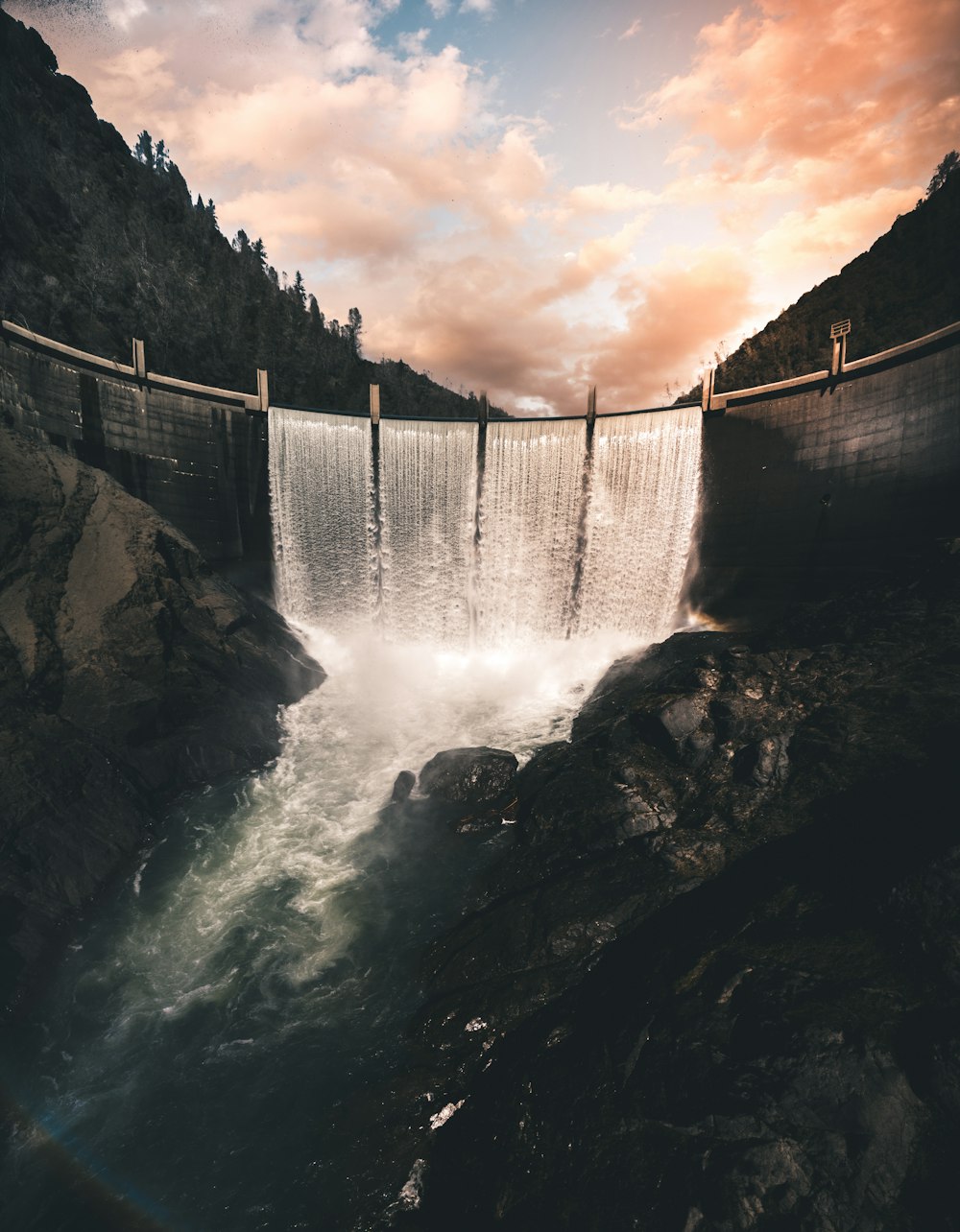 Graustufenfoto von Wasserfällen unter bewölktem Himmel