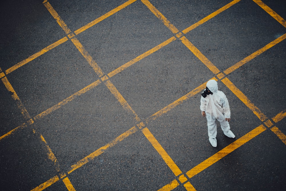 hombre en thobe blanco caminando sobre pavimento de hormigón gris y amarillo
