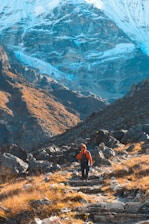 A hiker wearing ruggedpaths gear crossing a rocky mountain trail at sunrise.