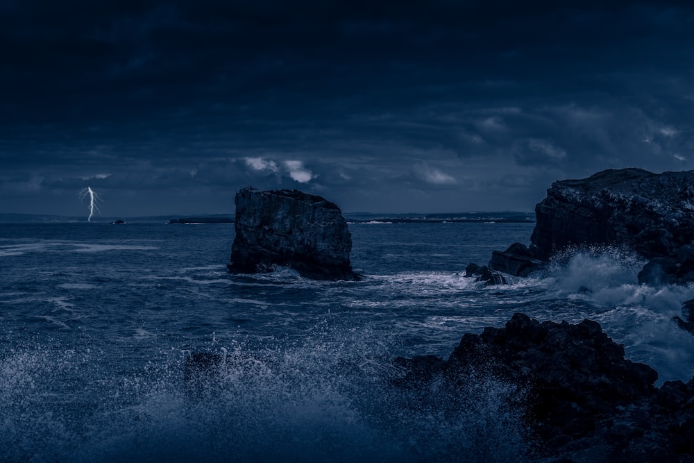 gray rock formation on sea water under gray clouds