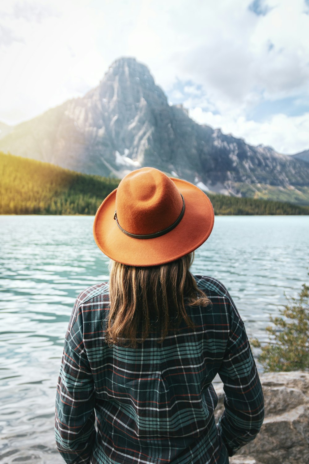 woman in brown fedora hat standing near lake during daytime