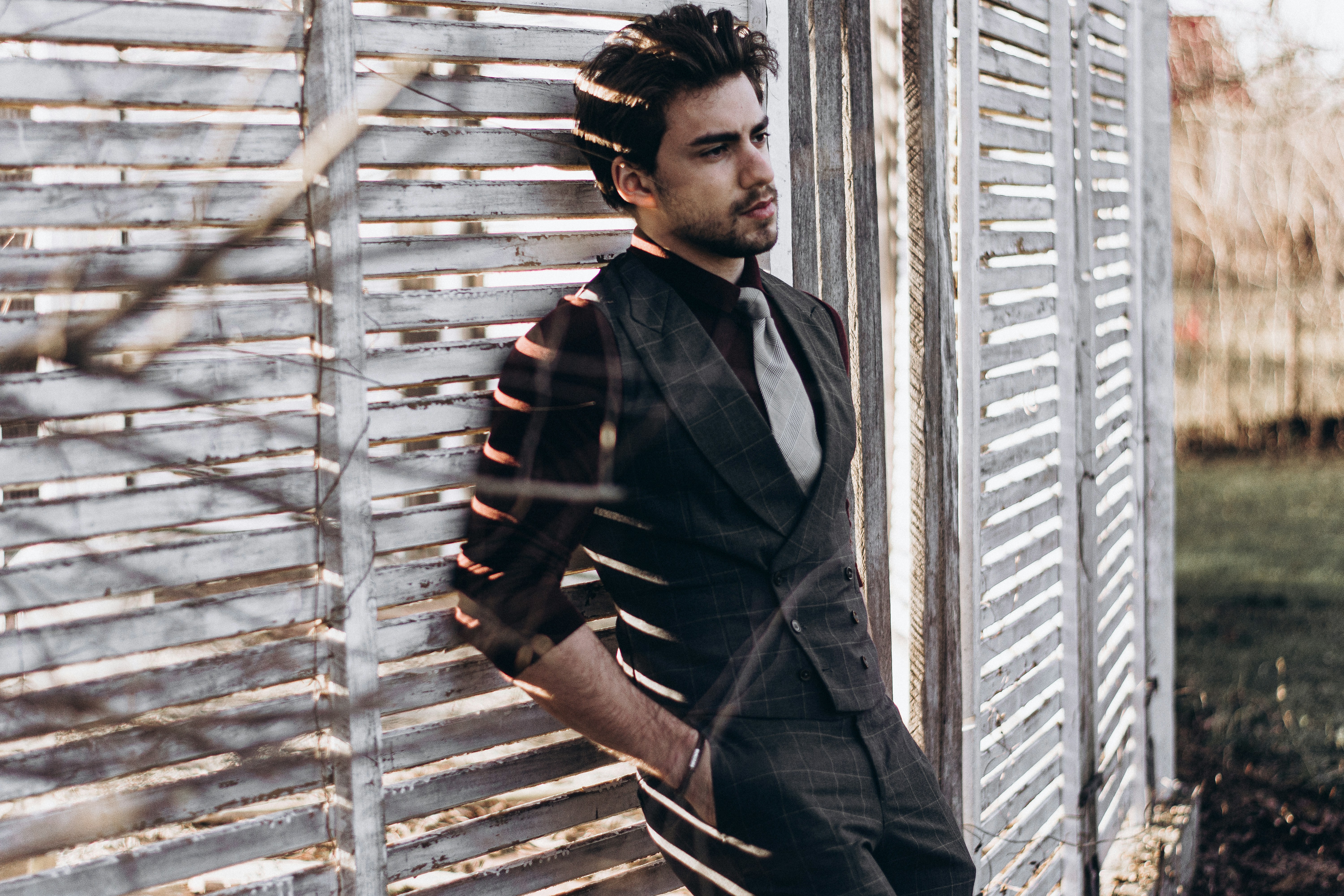 Man in suit leaning against a slatted wall