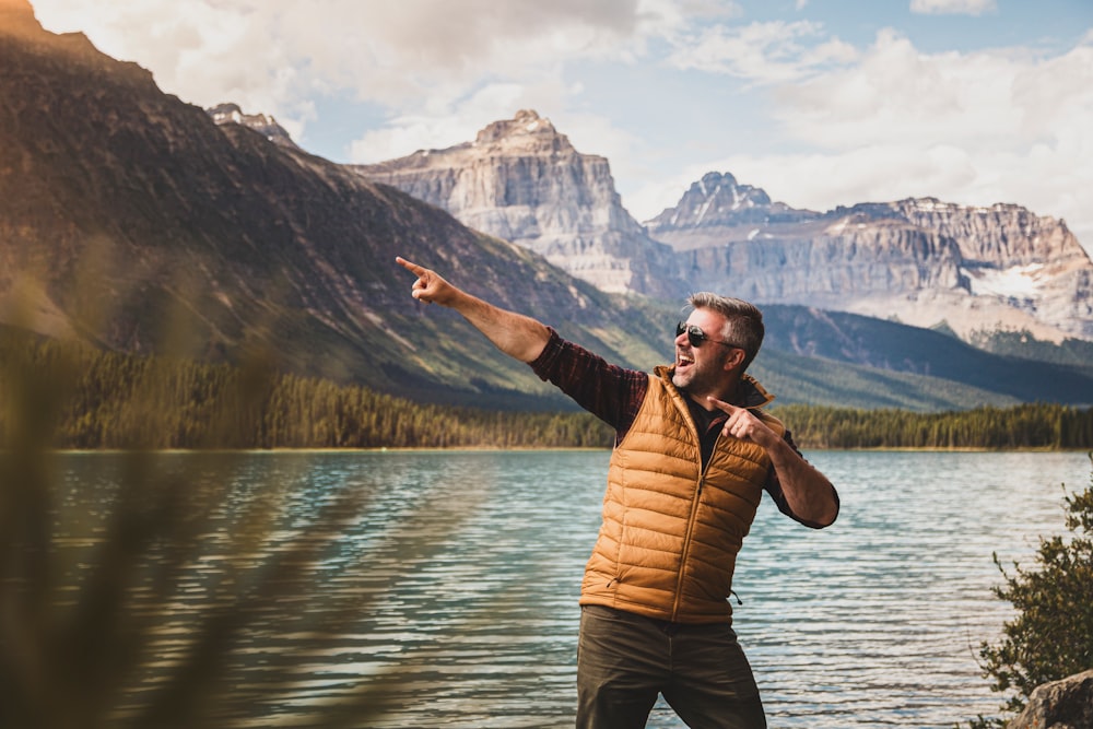 man in brown jacket standing on lake during daytime