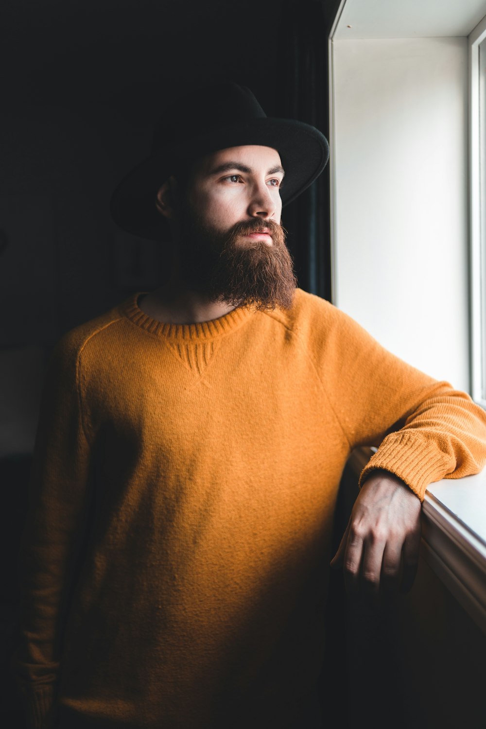 man in orange turtleneck sweater and black fedora hat