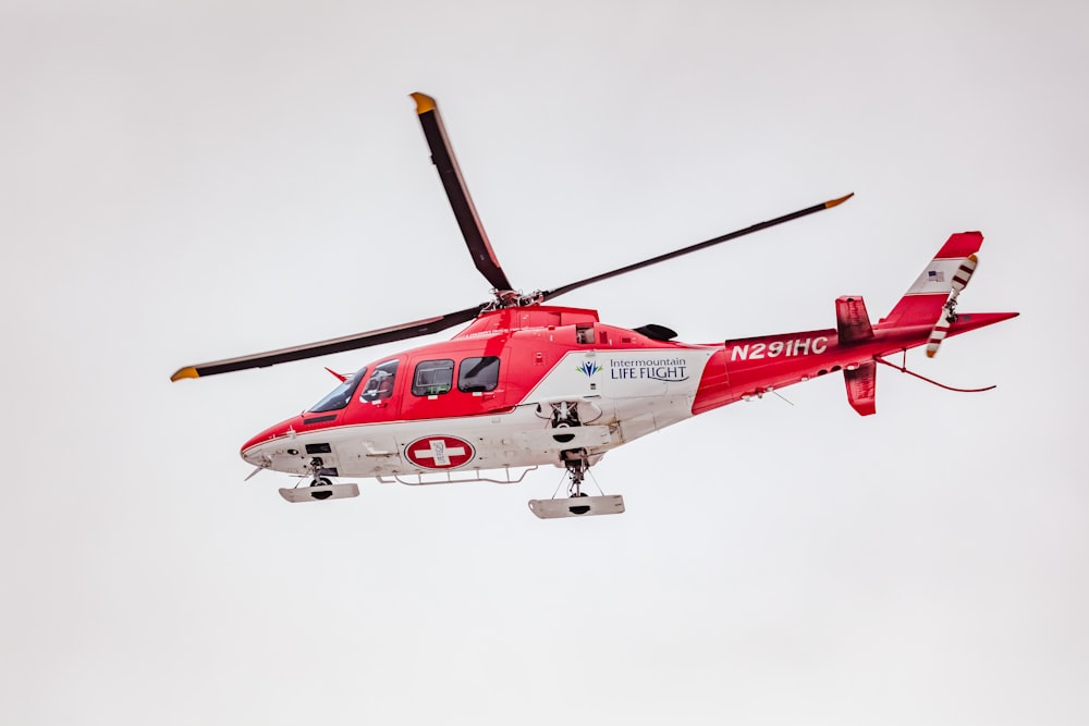 red and white helicopter flying in the sky