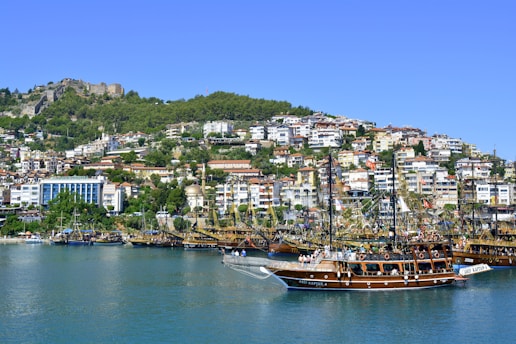 brown boat on body of water near city buildings during daytime