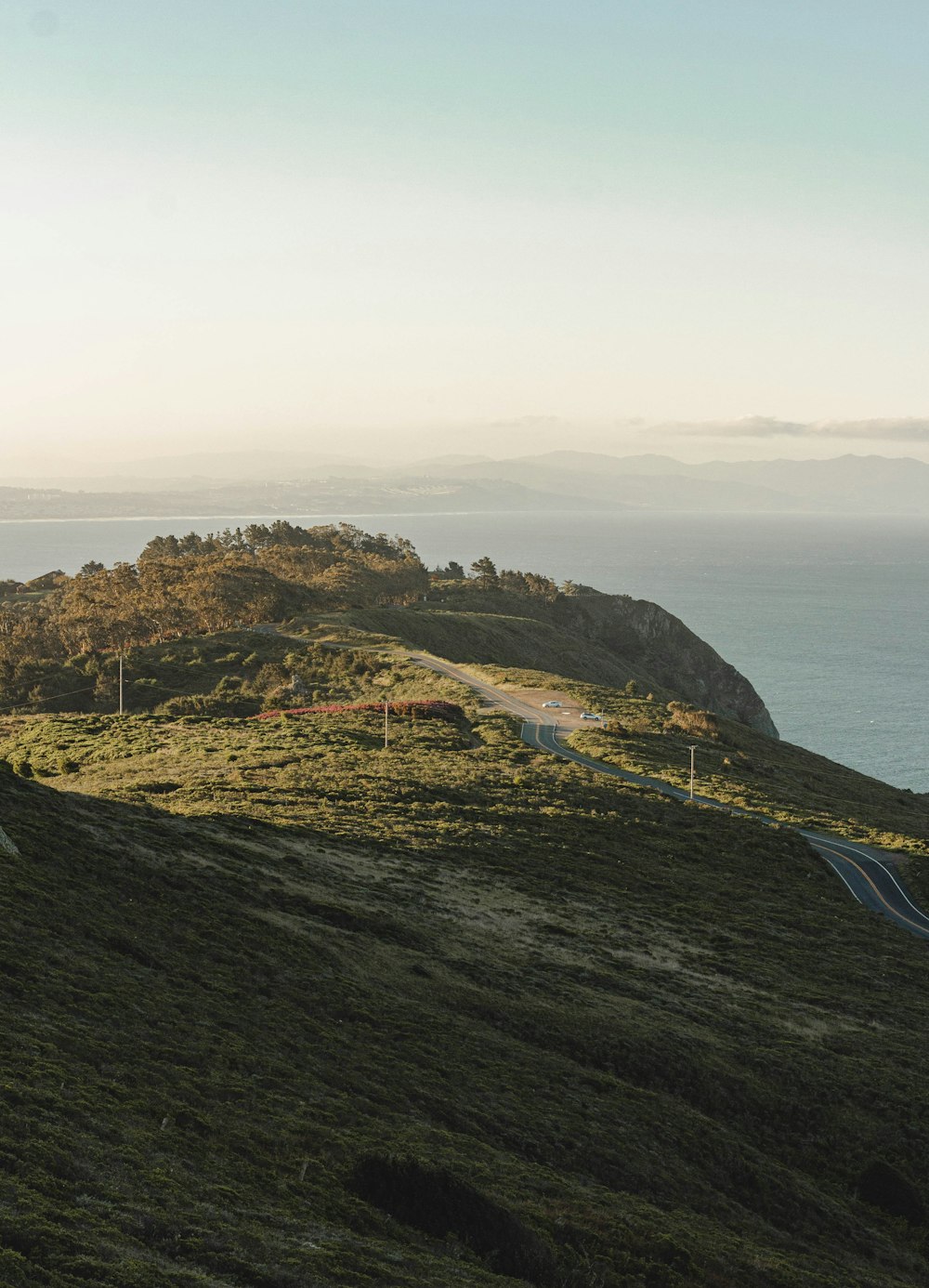 green and brown mountain beside blue body of water during daytime