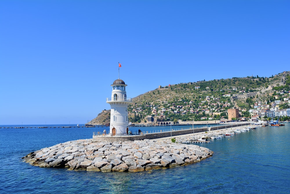 white and black lighthouse near body of water during daytime