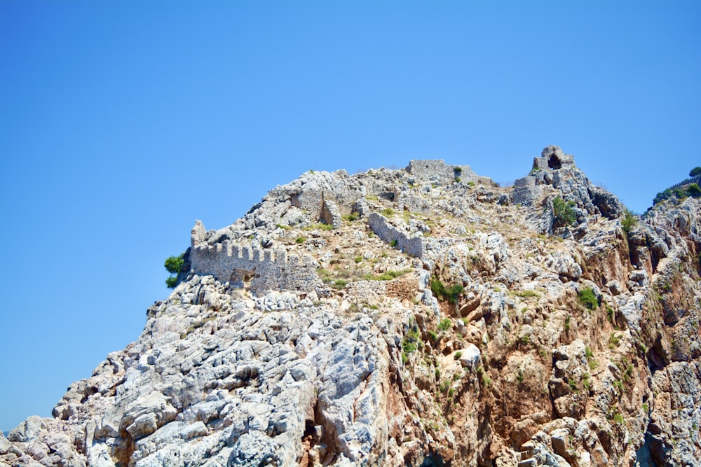 gray concrete building on rocky mountain under blue sky during daytime