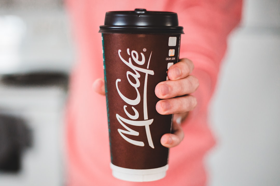 person holding brown and white disposable cup