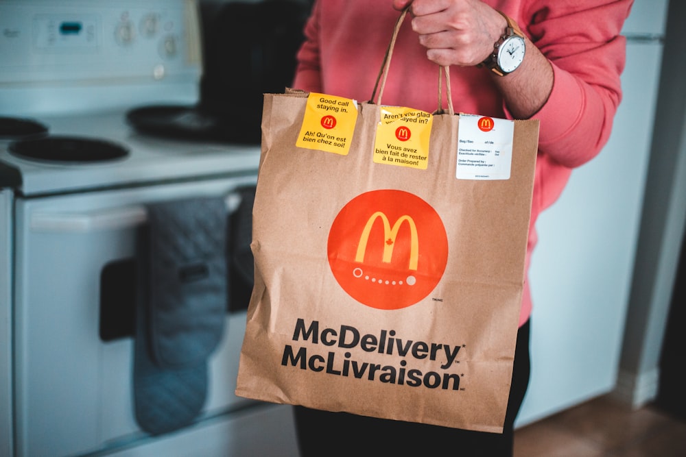 person holding brown and red paper bag