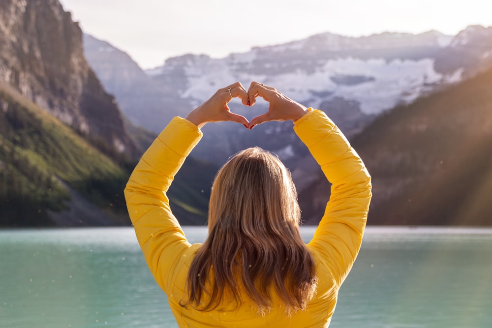 woman in yellow long sleeve shirt covering her face with her hands