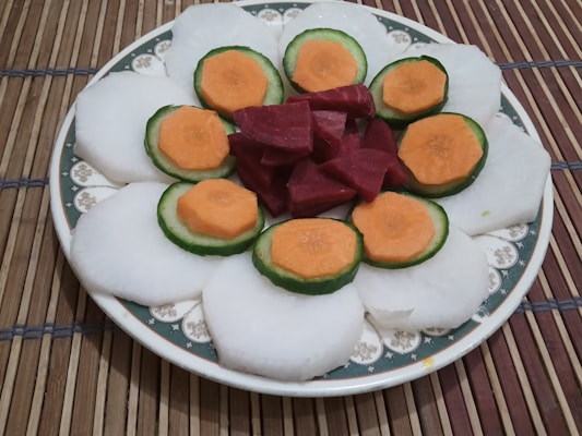 Fresh taro roots and sliced taro chips arranged on a natural fiber mat.