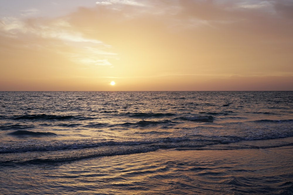 ocean waves crashing on shore during sunset