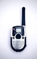 Close-up of a sleek two-way radio with illuminated buttons on a wooden desk.