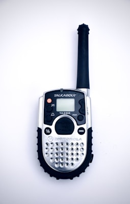 Close-up of a sleek handheld ham radio with illuminated buttons against a dark background.