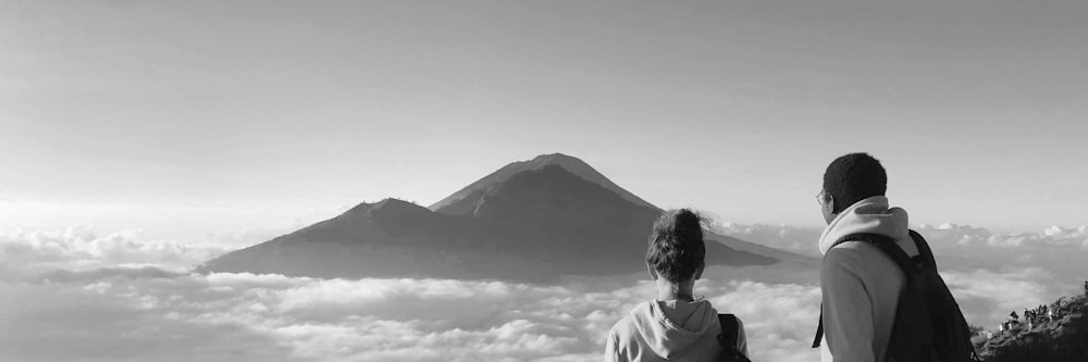 Photo en niveaux de gris d’un homme en chemise blanche regardant la montagne