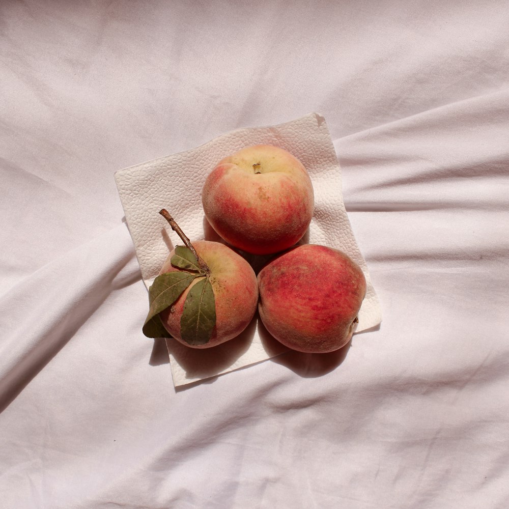 3 red apples on white textile