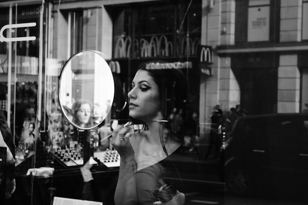 grayscale photo of woman holding magnifying glass