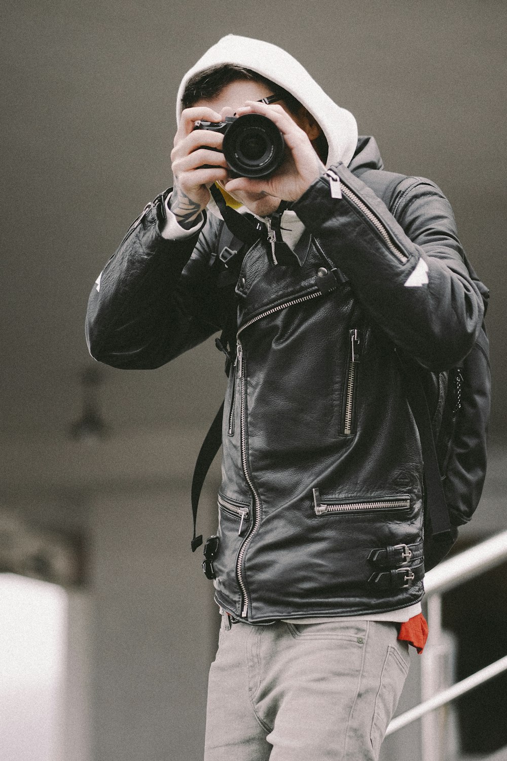 man in black leather jacket holding black camera