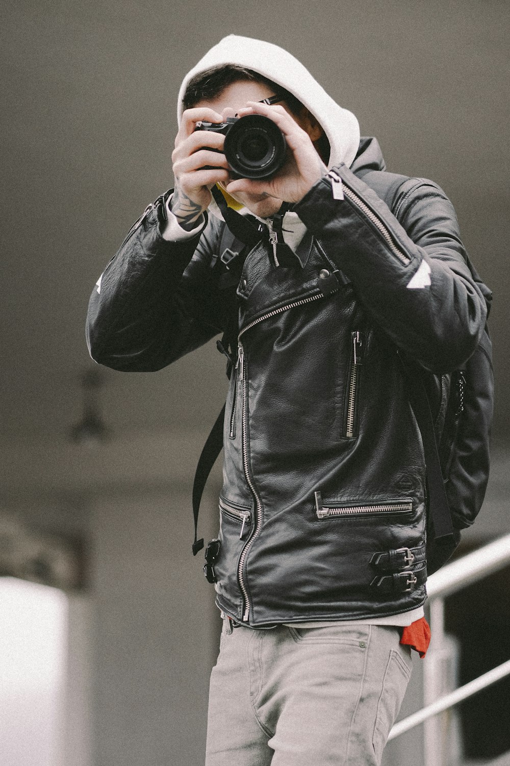 uomo in giacca di pelle nera che tiene la macchina fotografica nera