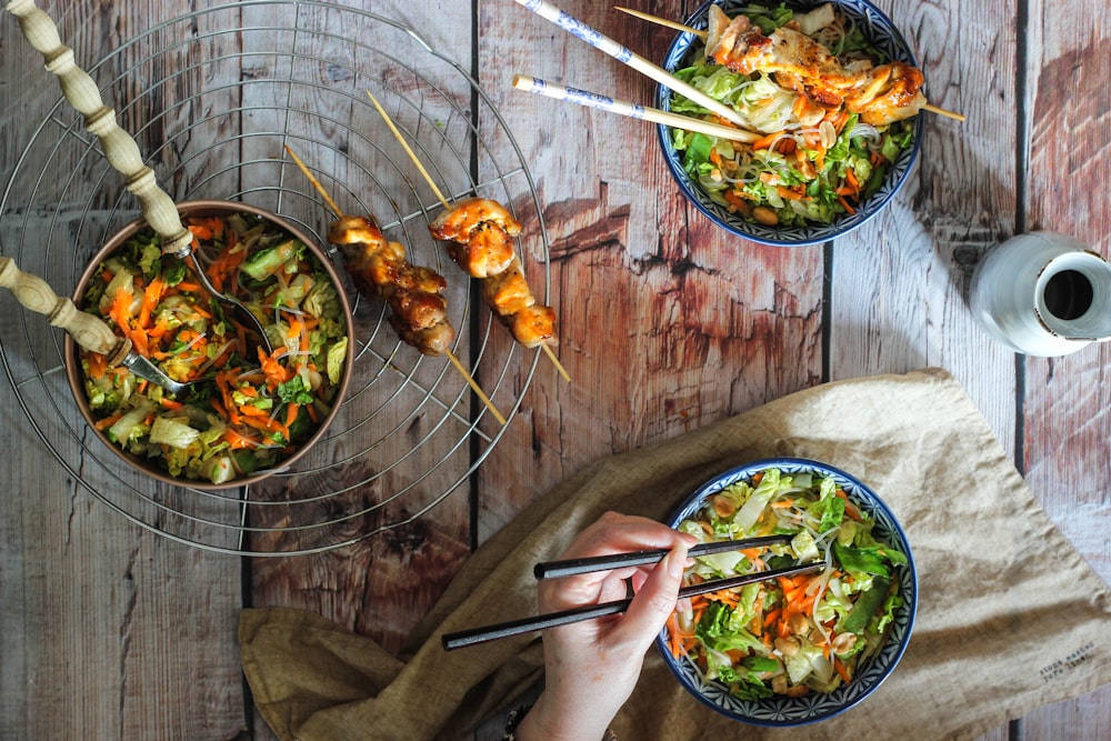 person holding chopsticks and fork eating cooked food