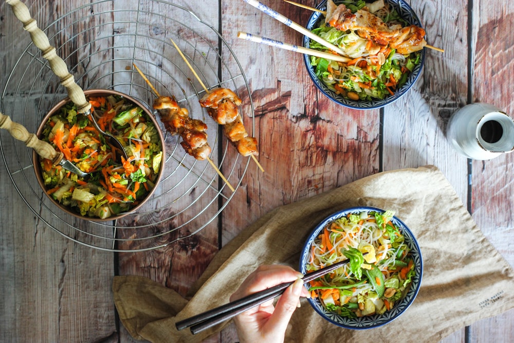 person holding chopsticks and fork eating cooked food