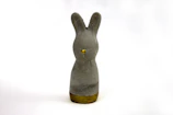 An artistic 3D printed bunny sculpture with a glossy finish, placed on a white pedestal against a soft background.