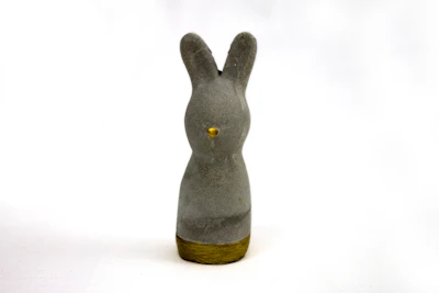 An artistic 3D printed bunny sculpture with a glossy finish, placed on a white pedestal against a soft background.