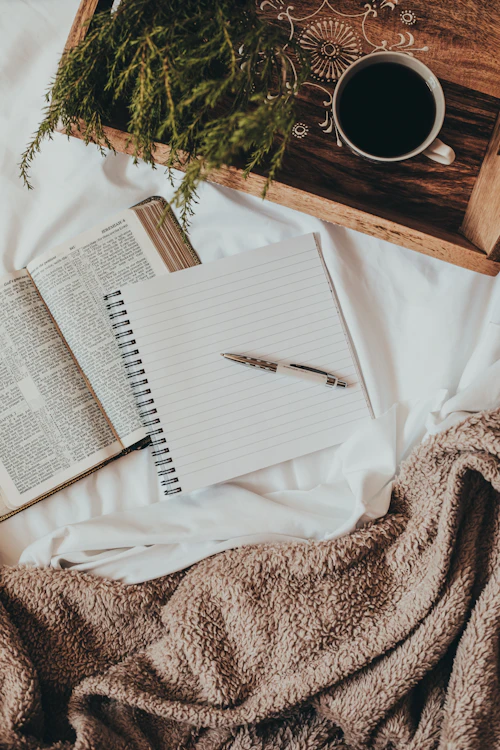 Cuaderno y taza de café junto a una planta, espacio de reflexión