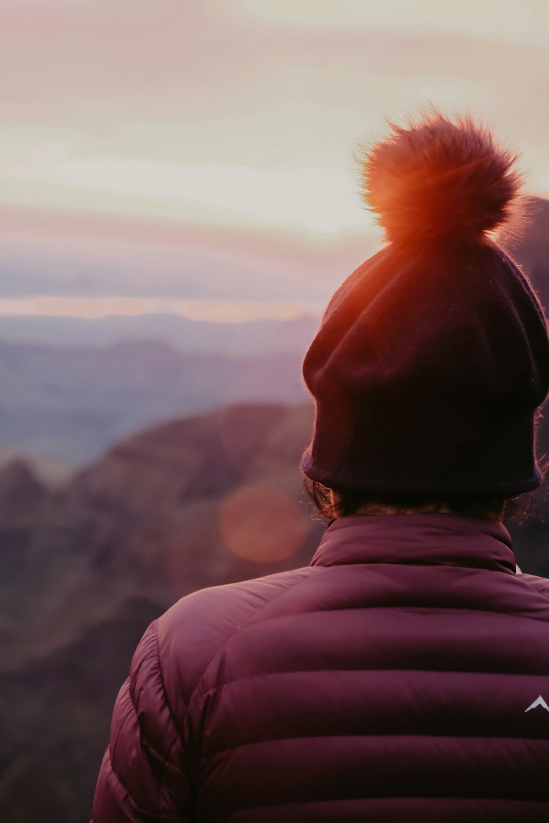 person in black knit cap and pink hoodie looking at the mountains during daytime