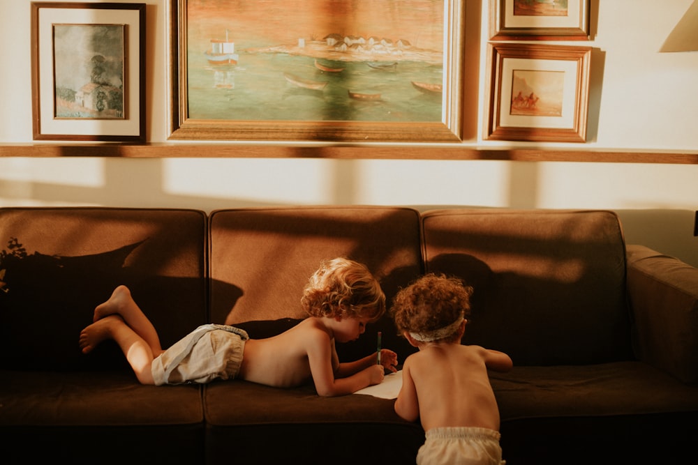 2 children sitting on brown couch