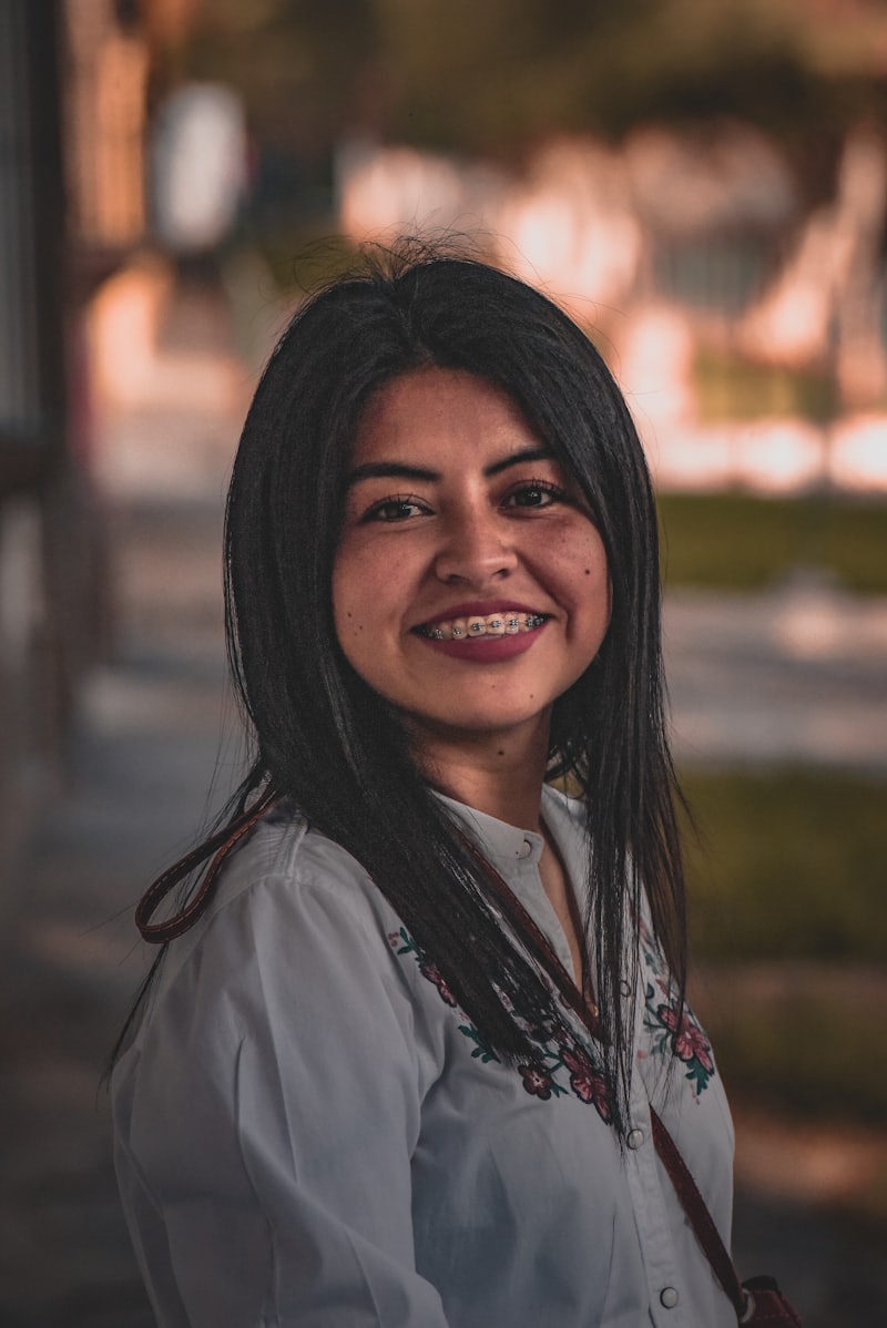 Mujer joven sonriendo con blusa blanca en la calle