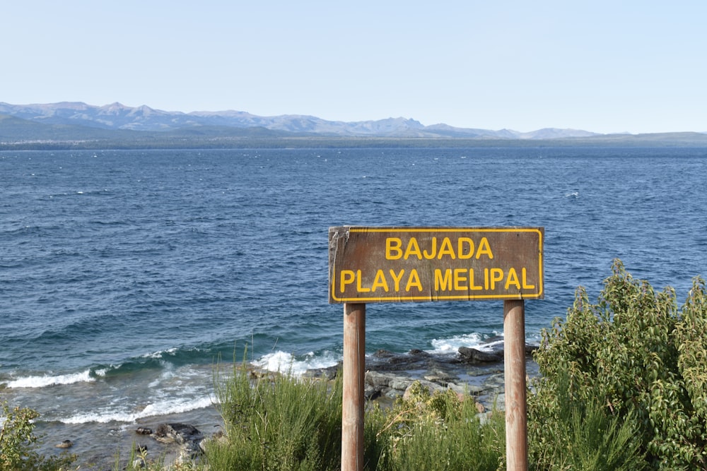 brown wooden beach signage near sea during daytime