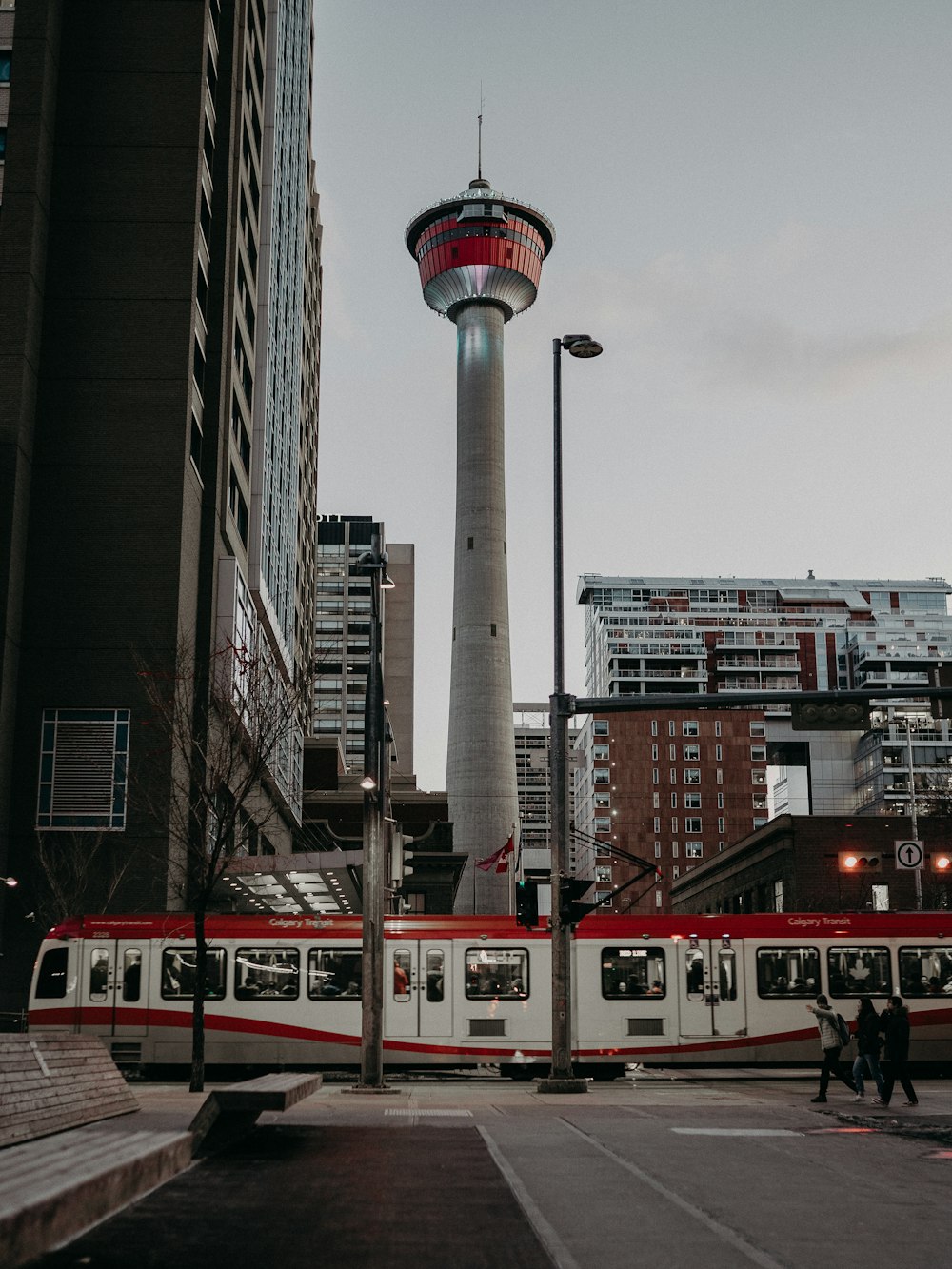 a red and white train traveling past tall buildings