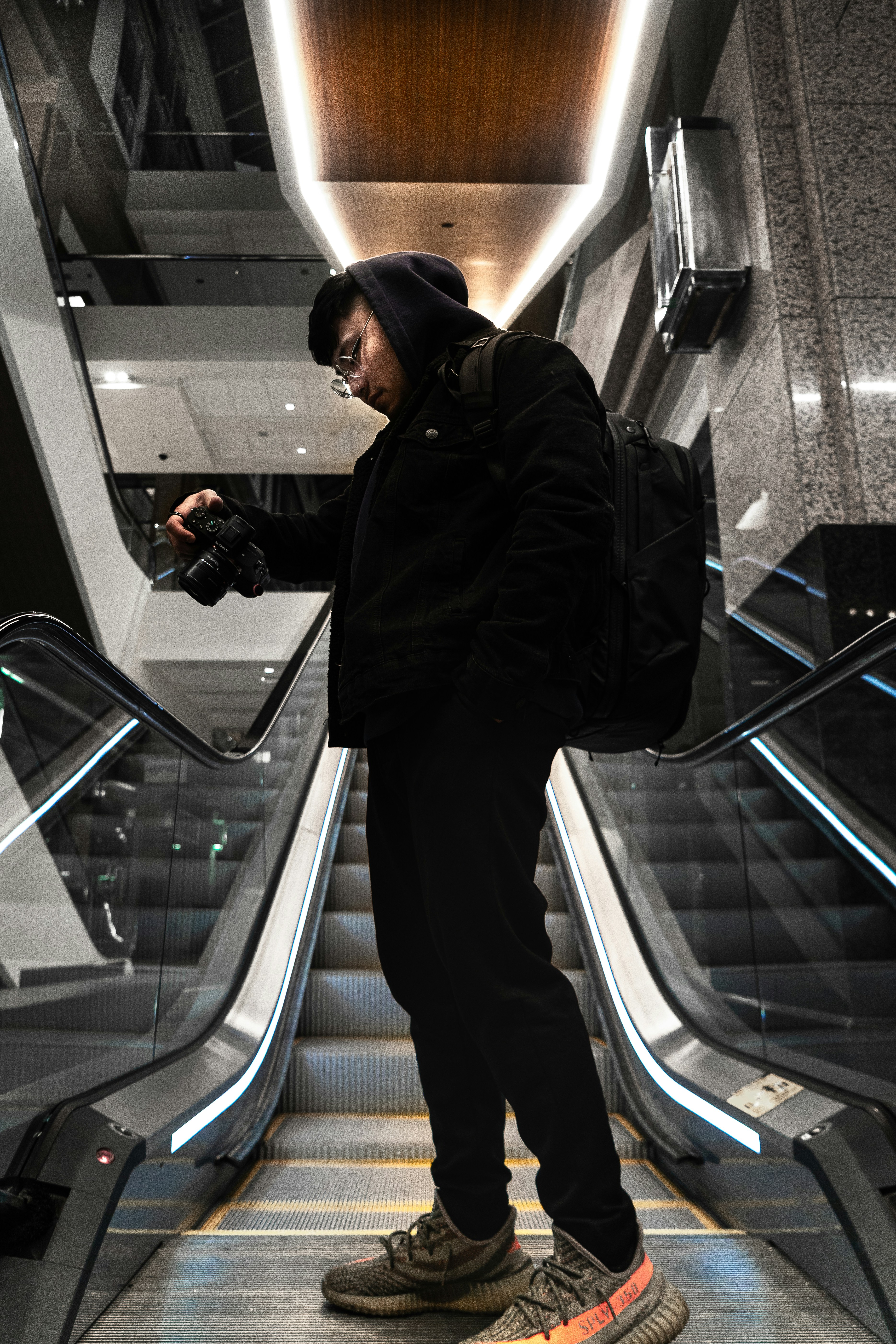 エスカレーターに立つ黒いジャケットと黒い帽子の男