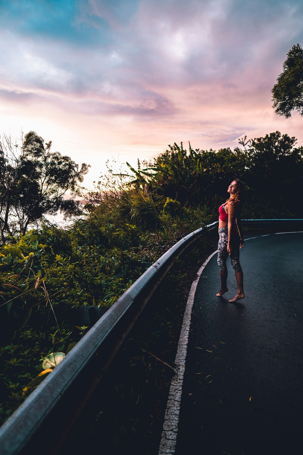 woman in red tank top and blue denim jeans walking on gray concrete road during daytime