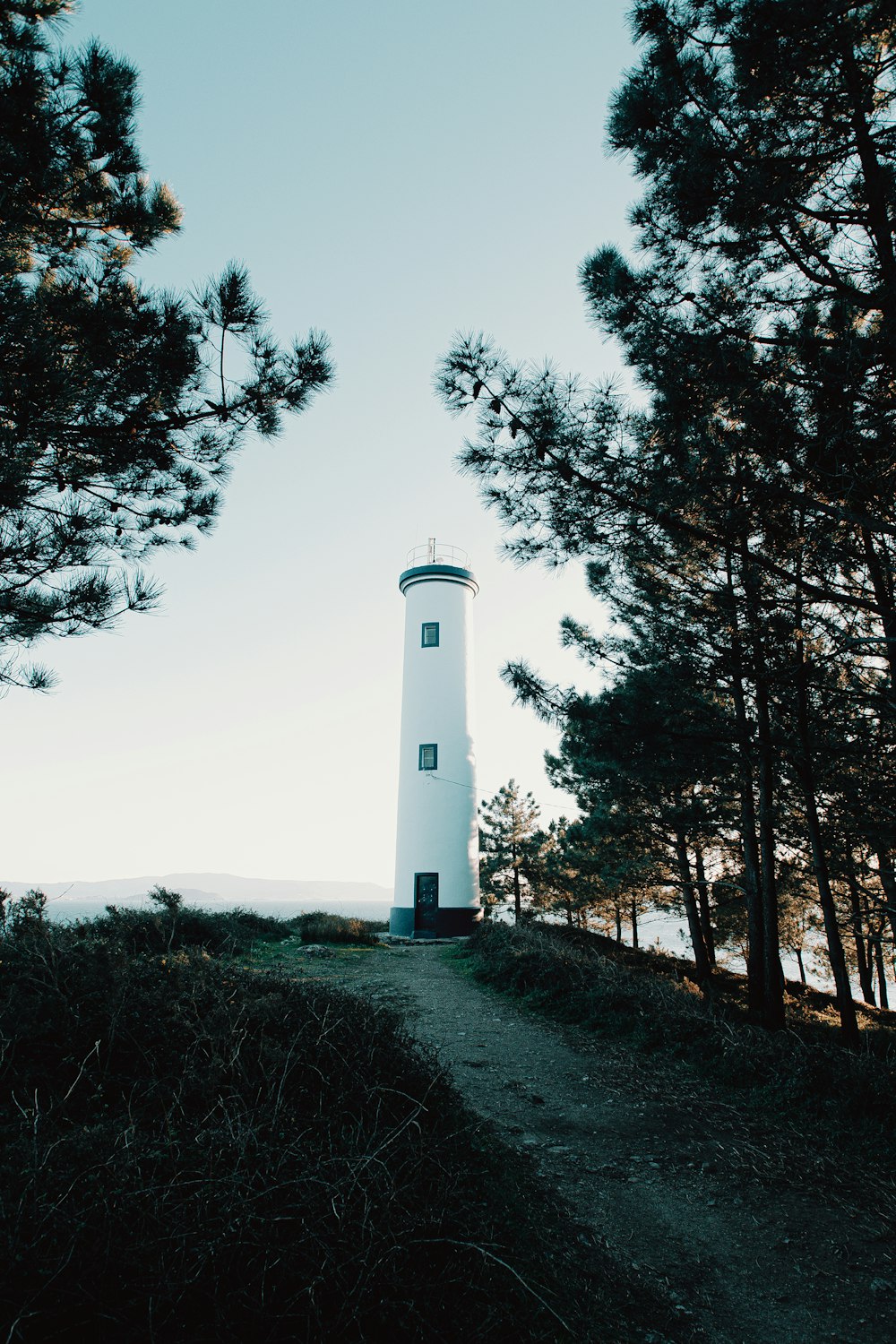 white lighthouse near green trees under white sky during daytime