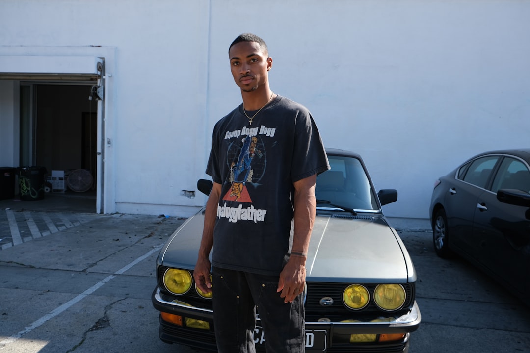 man in black crew neck t-shirt standing beside yellow car