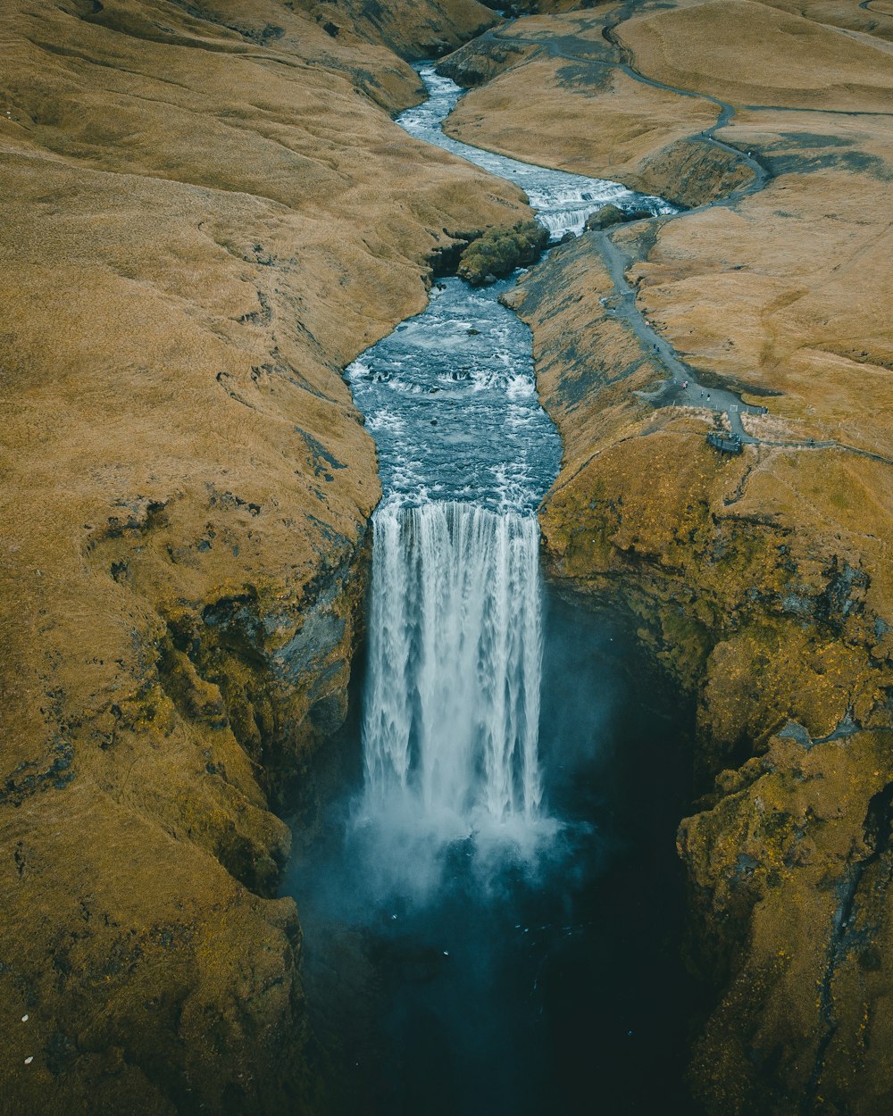 Chutes d’eau sur la montagne rocheuse brune pendant la journée