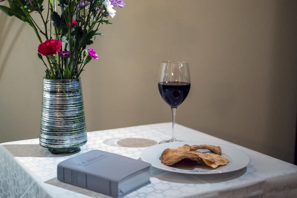 bread on white ceramic plate beside purple flowers in clear glass vase