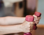 person holding pink and white dumbbells