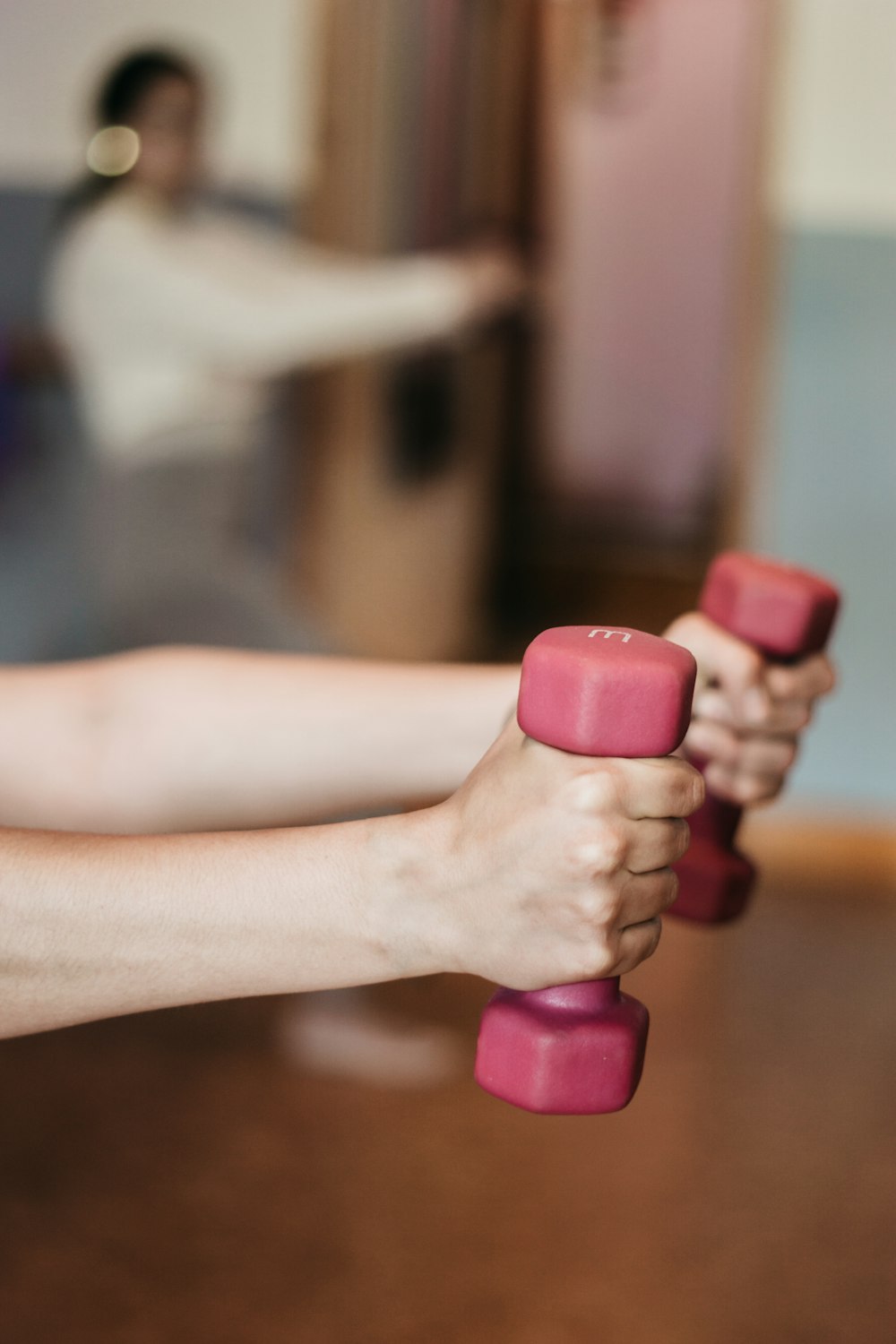 person holding pink and white dumbbells