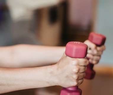 person holding pink and white dumbbells