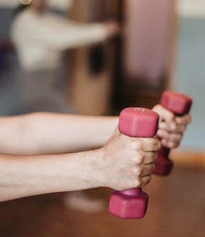 person holding pink and white dumbbells
