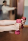 person holding pink and white dumbbells