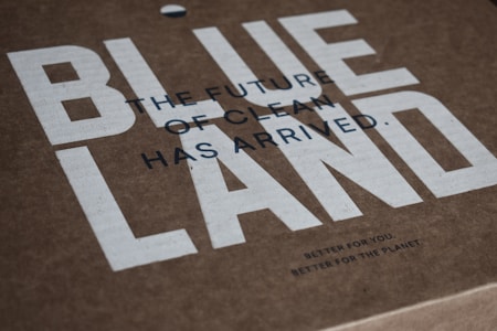 Brown cardboard packaging features bold white text that spells 'BLUELAND.' Smaller black text states 'THE FUTURE OF CLEAN HAS ARRIVED.' Below that, in much smaller text, it reads 'BETTER FOR YOU. BETTER FOR THE PLANET.' The overall look is minimalist with a focus on eco-friendliness.