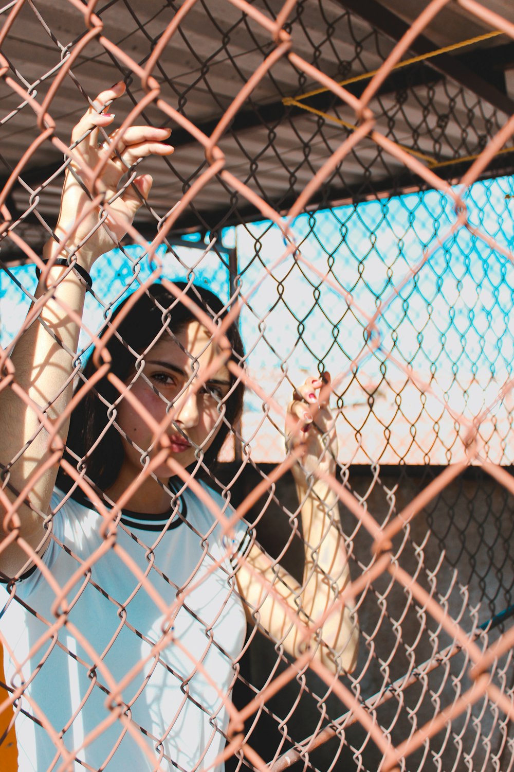 woman in white long sleeve shirt leaning on white metal fence during daytime