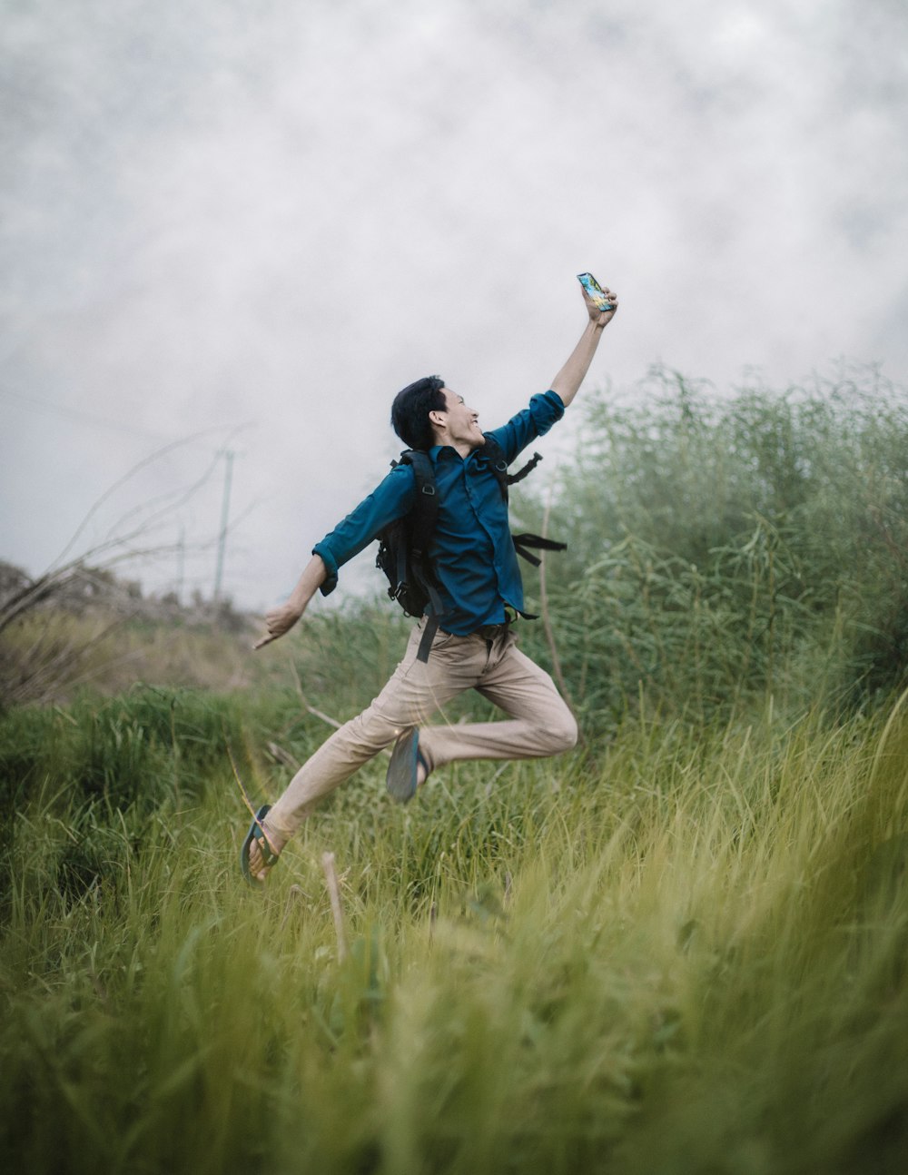 man in blue jacket and brown pants walking on green grass field during daytime